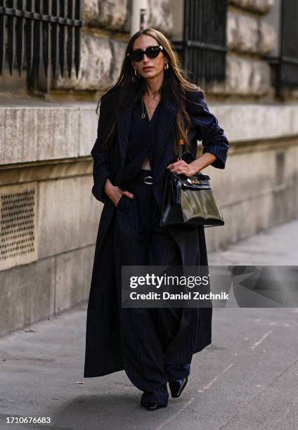 Chloe Harreuche is seen wearing a Hermes coat, blue top and pants with black sunglasses and an Hermes black bag outside the Hermes show during the...