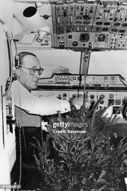 Prince Bernhard of the Netherlands in the cockpit of his private plane, with a christmas tree given to him by the people of Goslar after he visited...