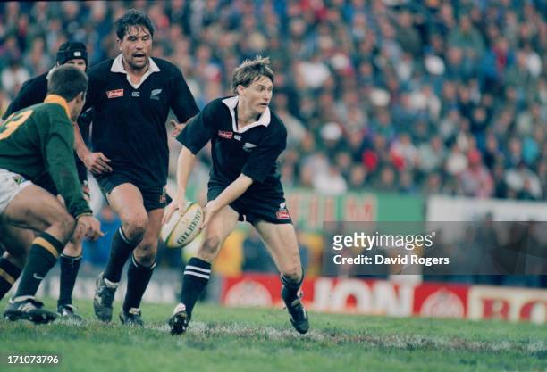 New Zealand All Blacks fly-half Andrew Mehrtens makes a pass as teammate Zinzan Brooke looks on, during the last match of the Tri Nations Series,...