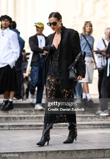 Guest is seen wearing a black blazer, black top, lace stockings and black boots with a black bag outside the Elie Saab show during the Womenswear...