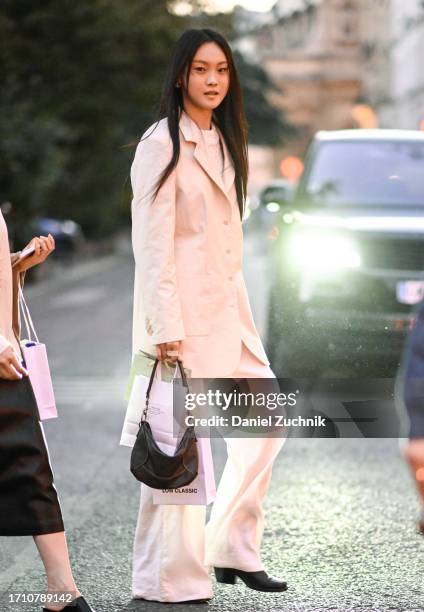 Model is seen wearing a white suit with black bag outside the Alexander McQueen show during the Womenswear Spring/Summer 2024 as part of Paris...