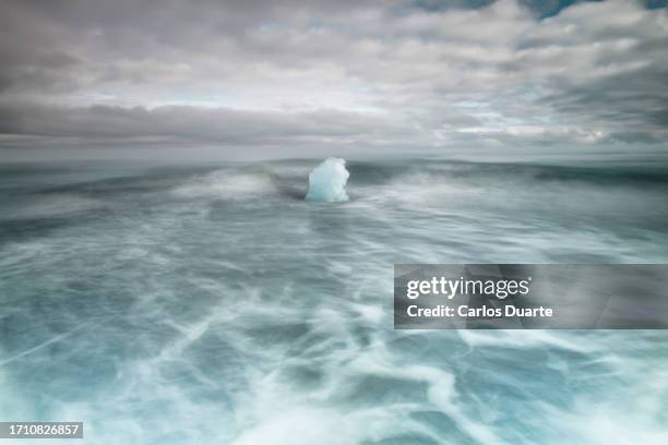 sea landscape from jokulsarlon volcanic beach of a lonely drifting iceberg - lava ocean stock pictures, royalty-free photos & images