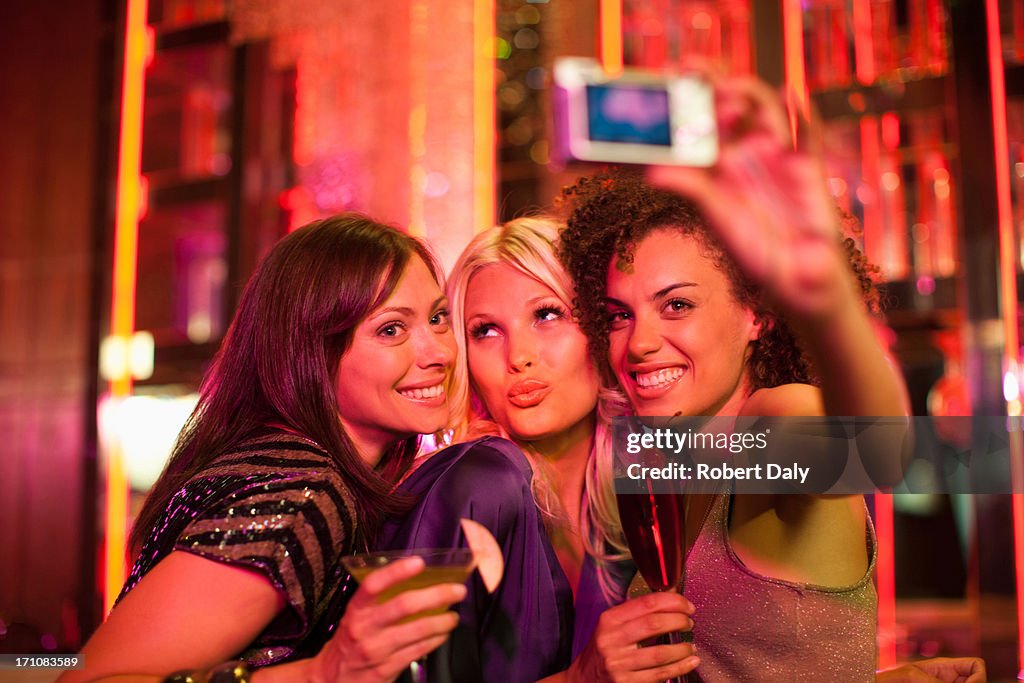 Friends in nightclub taking self-portrait with digital camera