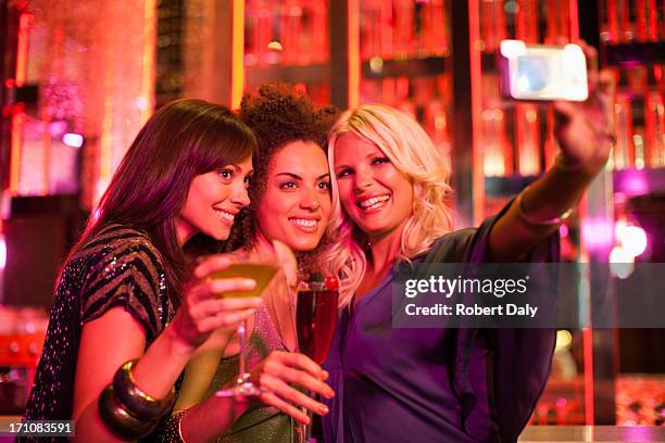 friends in nightclub taking self-portrait with digital camera - mid adult women stock pictures, royalty-free photos & images