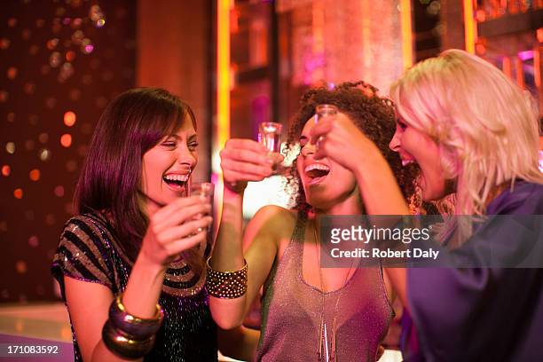 friends toasting shot glasses in nightclub - girls night out stockfoto's en -beelden