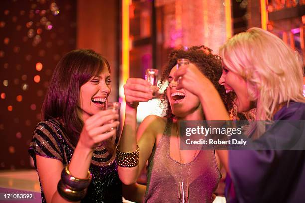 friends toasting shot glasses in nightclub - shot glass stock pictures, royalty-free photos & images