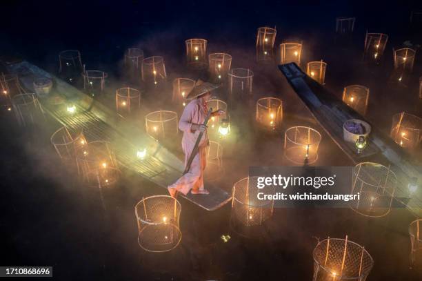 fisherman with traditional fish trap at night, inle lake, myanmar - myanmar skyline stock pictures, royalty-free photos & images