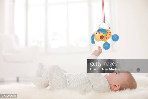 baby auf teppich greifen zum aufhängen spielzeug über - kinder spielzeug stock-fotos und bilder