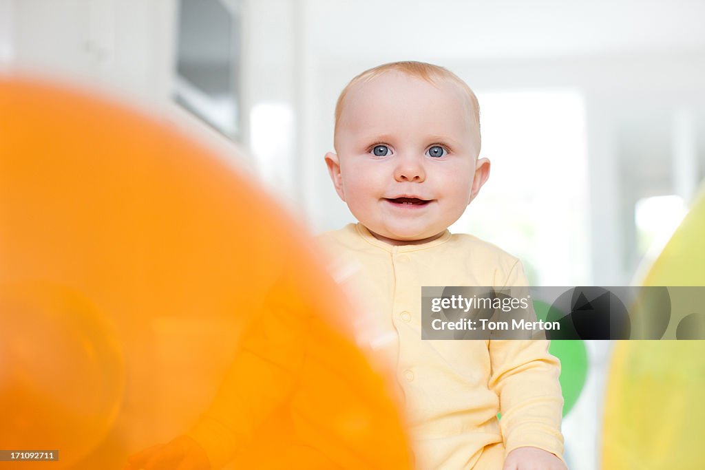 Smiling baby with balloons on floor