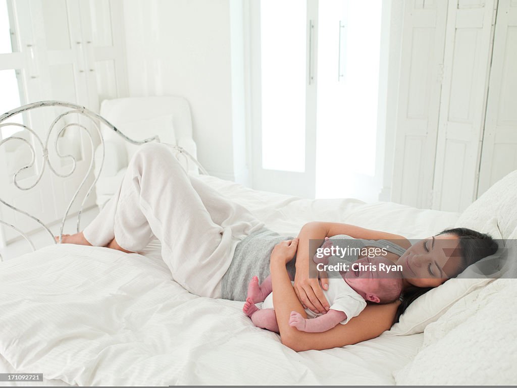 Smiling mother laying in bed with baby