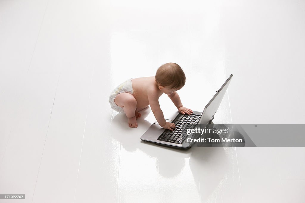 Baby on floor reaching for laptop