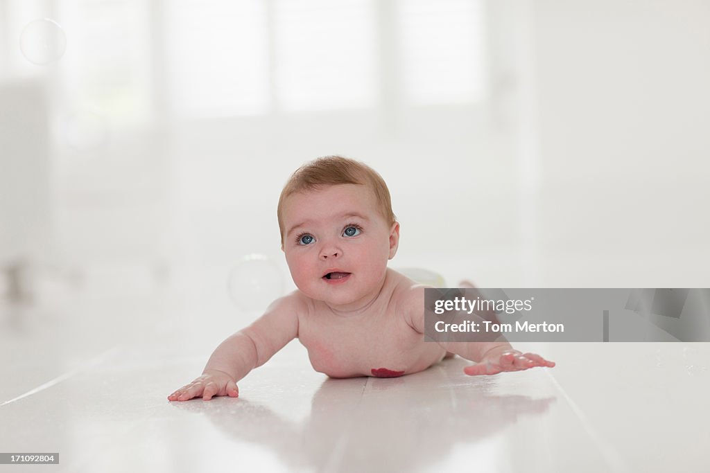 Smiling baby laying on floor and playing with bubbles