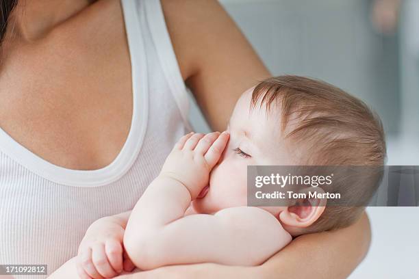 primer plano de la madre sostiene un bebé durmiendo chuparse el pulgar - chuparse el pulgar fotografías e imágenes de stock