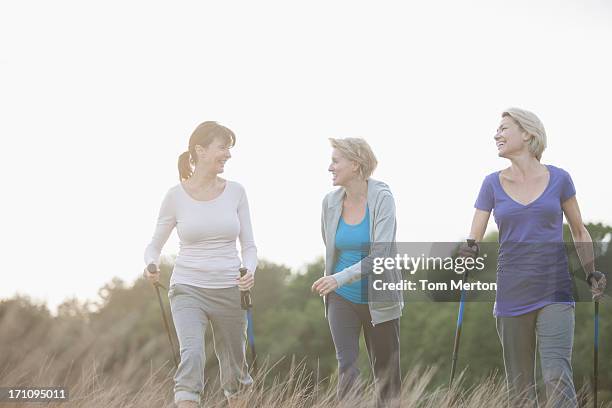 happy women hiking together outdoors - nordic walking stock pictures, royalty-free photos & images