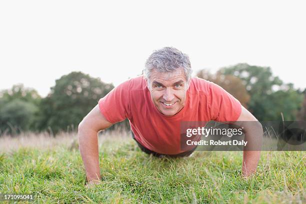 smiling man doing push-ups in field - waist up stock pictures, royalty-free photos & images