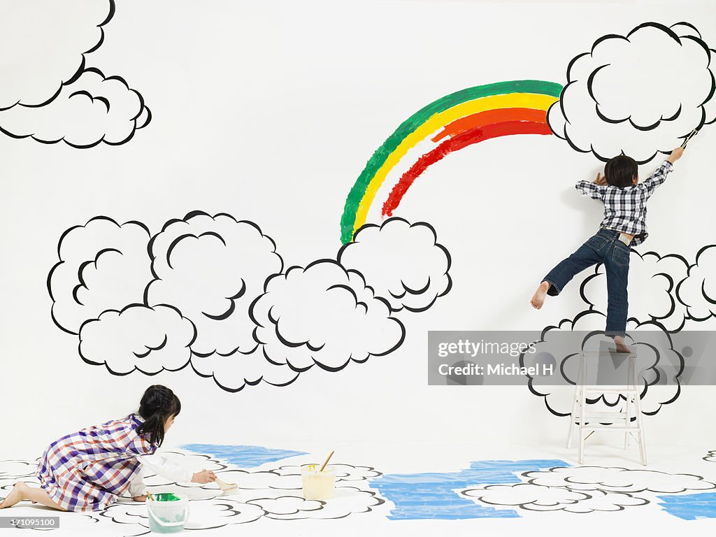 Children painting rainbow and cloud on the wall