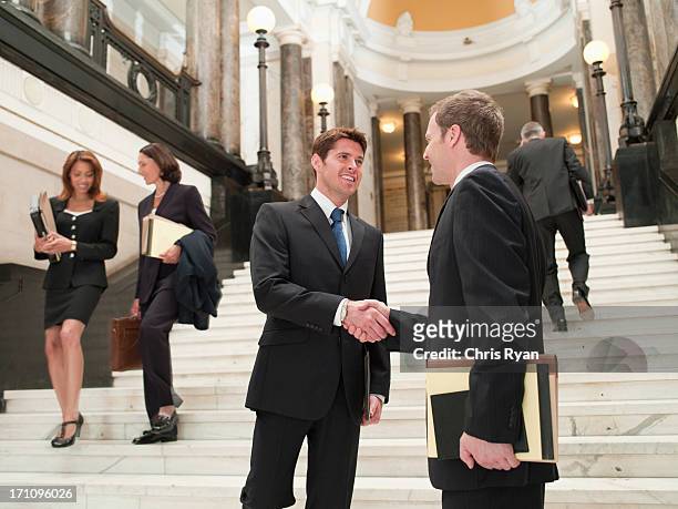 smiling lawyers shaking hands on stairs - lawyer handshake stock pictures, royalty-free photos & images