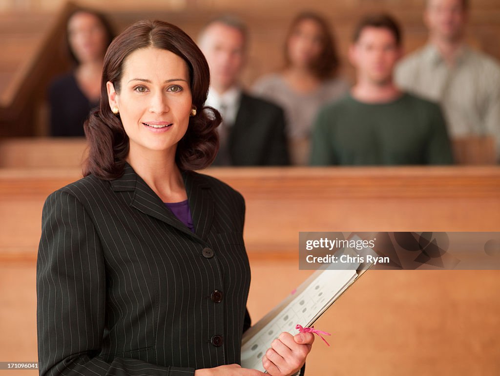 Smiling lawyer holding file in courtroom