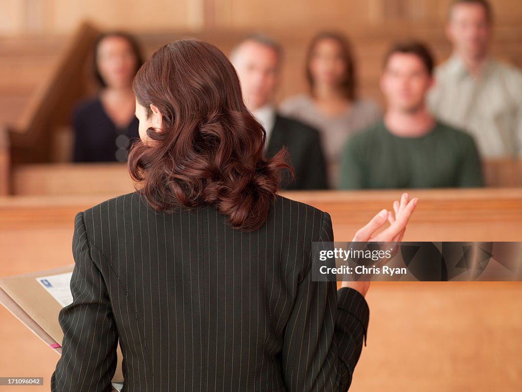 Lawyer holding document and speaking to jury in courtroom