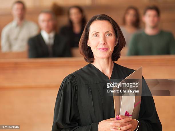 sorridente tenendo un file in aula di tribunale giudice - difensore foto e immagini stock