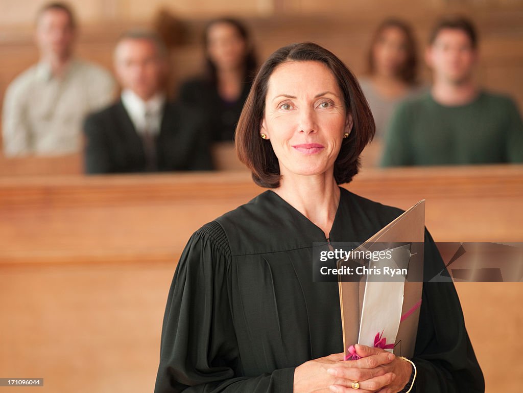 Smiling judge holding file in courtroom