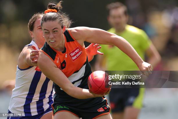 Emily Pease of the Giants handballs under pressure from Jasmine Garner of the Kangaroos during the round five AFLW match between North Melbourne...