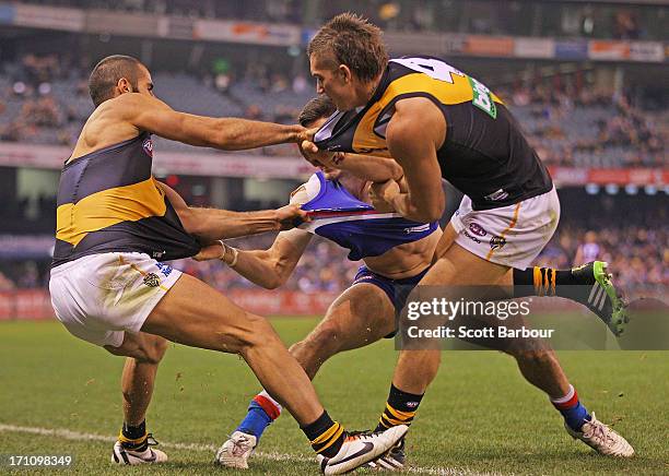 Nick Lower of the Bulldogs and Dustin Martin and Bachar Houli of the Tigers wrestle during the round 13 AFL match between the Western Bulldogs and...
