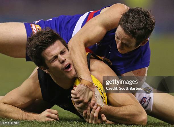 Trent Cotchin of the Tigers is tackled by Robert Murphy of the Bulldogs during the round 13 AFL match between the Western Bulldogs and the Richmond...