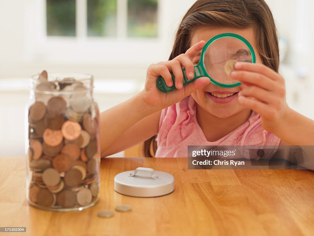 Girl looking at coin with magnifying glass