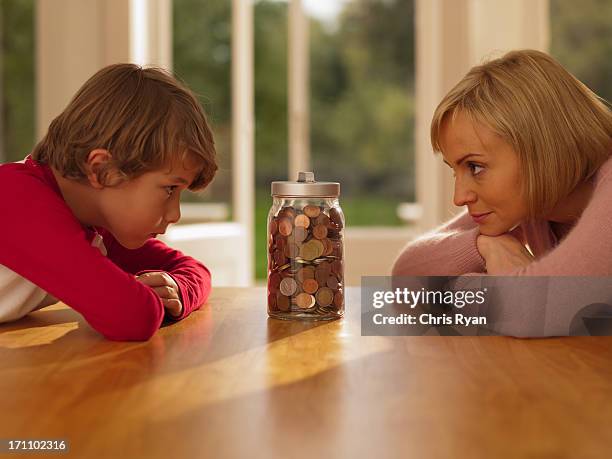 mother and son looking at jar full of coins - full responsibility stock pictures, royalty-free photos & images