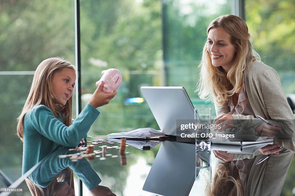 Mother watching daughter count coins from piggy bank