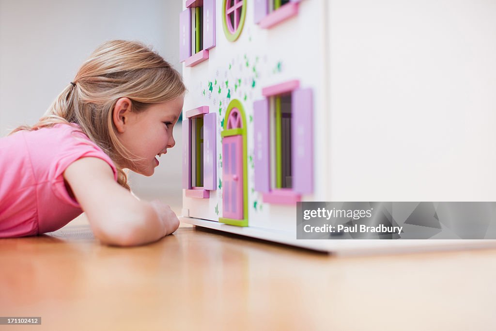 Girl peering into dollhouse