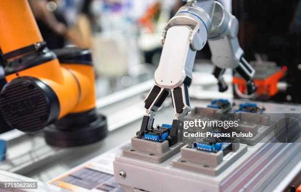 industrial robot holding operating a robot machine with a control panel - cadena objeto fabricado fotografías e imágenes de stock