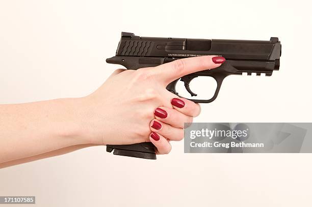 woman holding pistol, finger off trigger - hand holding gun stock pictures, royalty-free photos & images