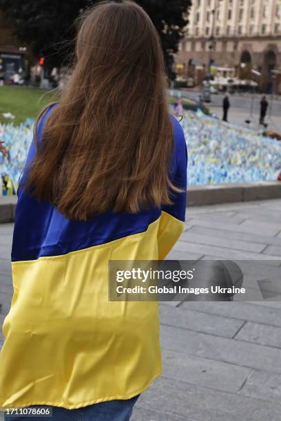 Girl wrapped in the Ukrainian flag stands near a spontaneous memorial to fallen Ukrainian soldiers on October 1, 2023 in Kyiv, Ukraine. Ukraine...