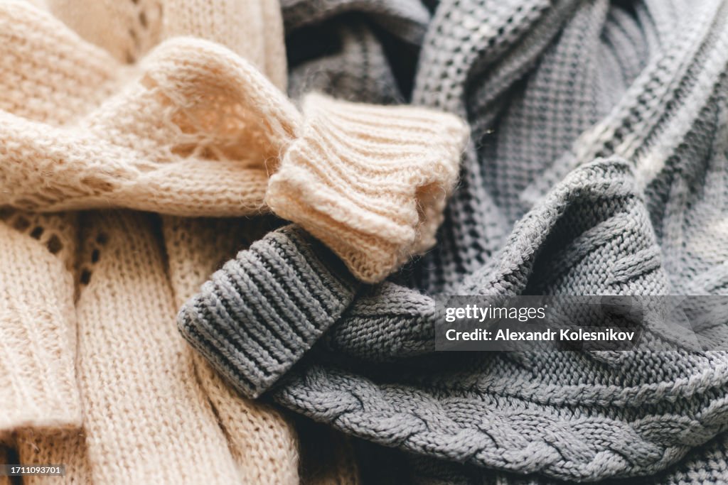 Knitted warm grey and beige sweaters or scarf. Fabric knitted texture close up background.