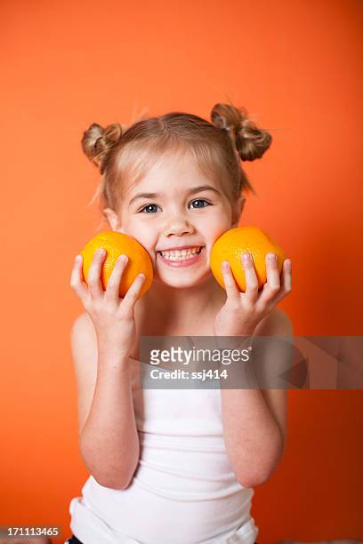 cute little girl with oranges on orange background - food close up stock pictures, royalty-free photos & images
