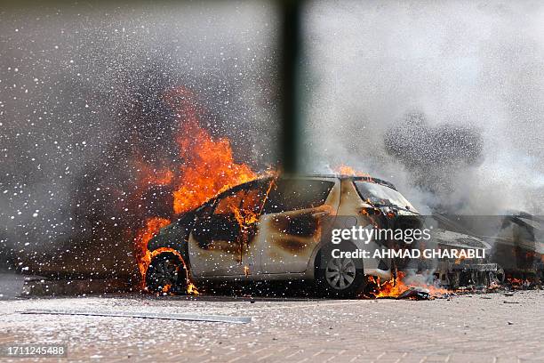 Cars are seen on fire following a rocket attack from the Gaza Strip in Ashkelon, southern Israel, on October 7, 2023. Barrages of rockets were fired...