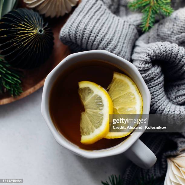winter still life. cozy composition with cup of tea with lemon, warm sweater and festive decoration on table - herpes labial - fotografias e filmes do acervo