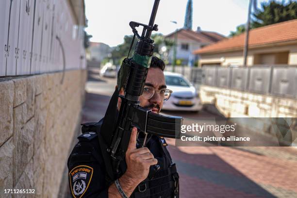 October 2023, Israel, Ashkelon: An Israeli police officer takes cover behind a wall during a rocket attack from Gaza. Palestinian militants in Gaza...