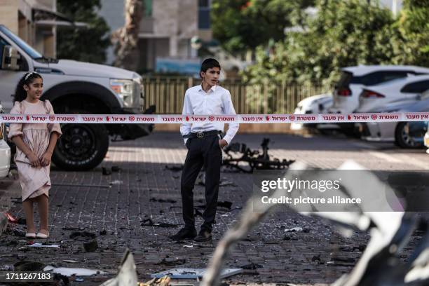 October 2023, Israel, Ashkelon: Residents look at the wreckage of destroyed vehicles following a rocket attack from Gaza. Palestinian militants in...