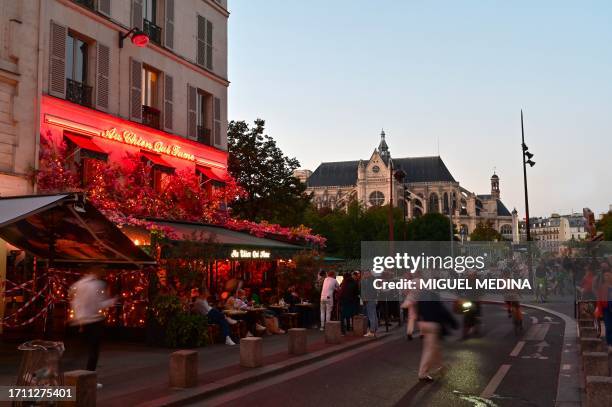 Pedestrians walk by the terrace of a cafe near Saint Eustache church in the 1st arrondissement of Paris on October 6, 2023.