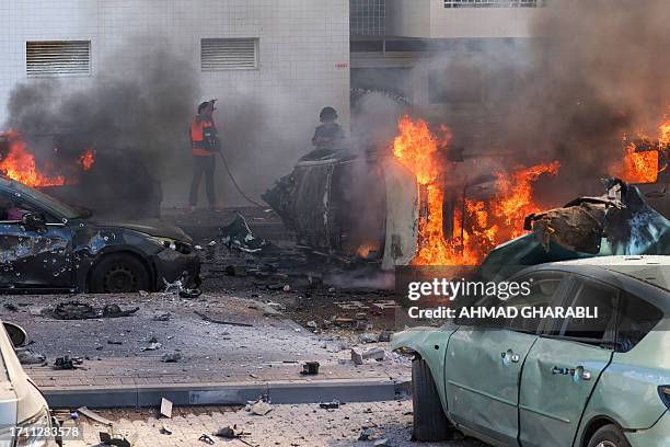 People try to extinguish fire on cars following a rocket attack from the Gaza Strip in Ashkelon, southern Israel, on October 7, 2023. Palestinian...