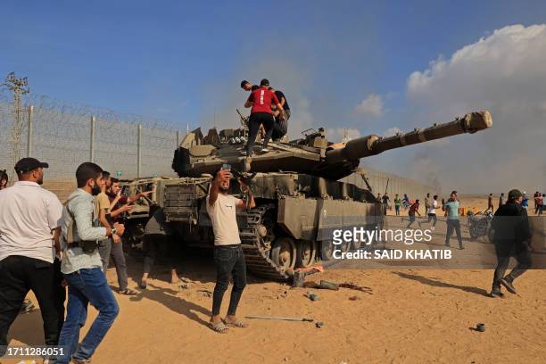 Palestinians take control of an Israeli Merkava battle tank after crossing the border fence with Israel from Khan Yunis in the southern Gaza Strip on...