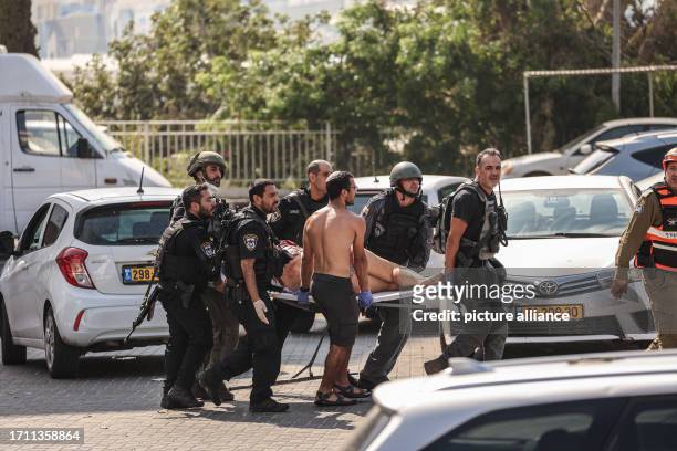 October 2023, Israel, Ashkelon: Members of Israeli security forces carry an injured person on a stretcher following a rocket attack from the Gaza....