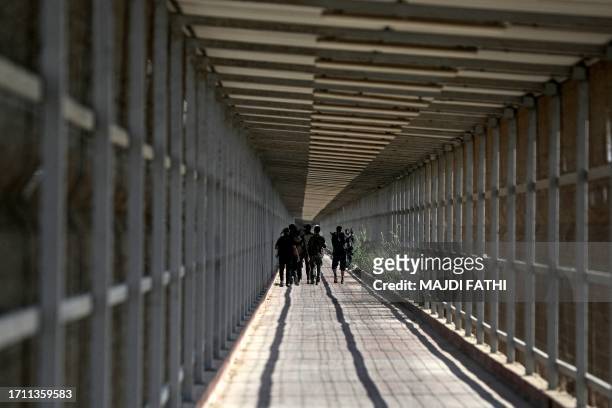 Palestinians and militants from the Ezzedine al-Qassam Brigades run towards the Erez crossing between Israel and the northern Gaza Strip on October...