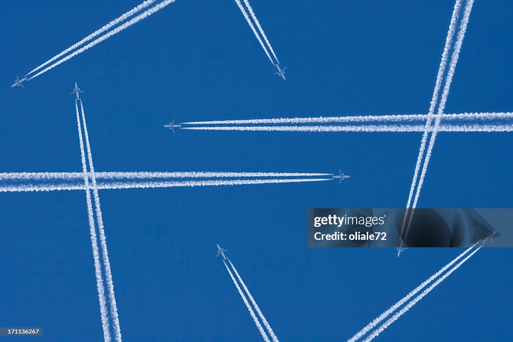 Vapor trails from airplanes in mid-air against a blue sky