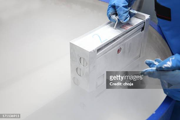 container with liquid nitrogen...doctor in hazmat suit at work - liquid nitrogen stockfoto's en -beelden