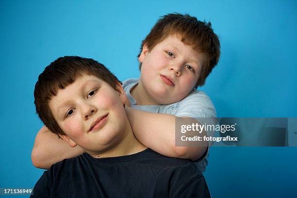 hermanos: linda sobrepeso niños frente de azul de pared - fat redhead fotografías e imágenes de stock