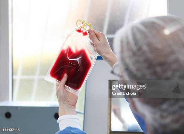 in  blood bank...doctor in hazmat suit is checking blood bag - blood bag stock pictures, royalty-free photos & images